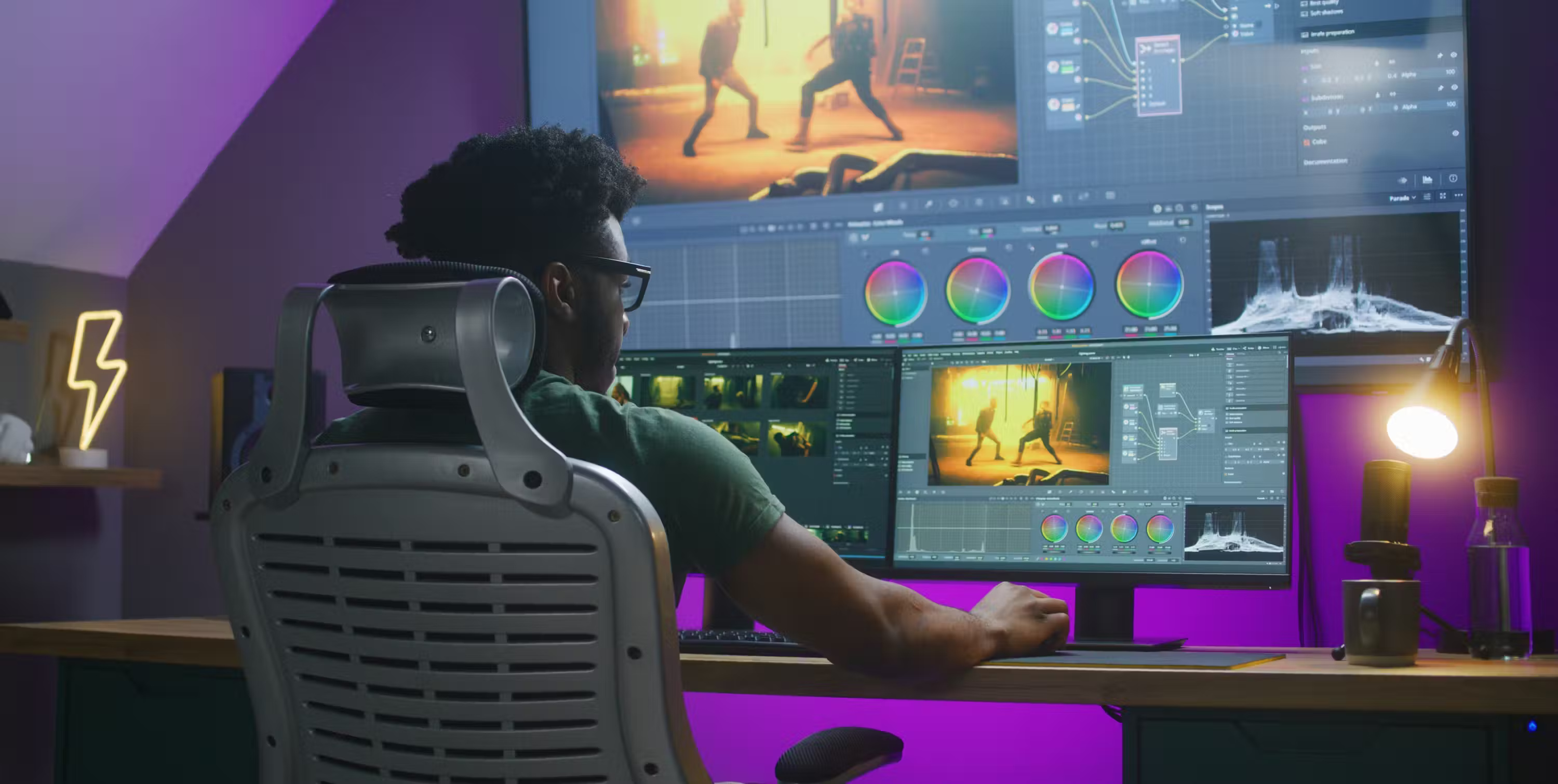 Một người đàn ông ngồi trước máy tính nhiều màn hình đang thực hiện quán trình Color grading